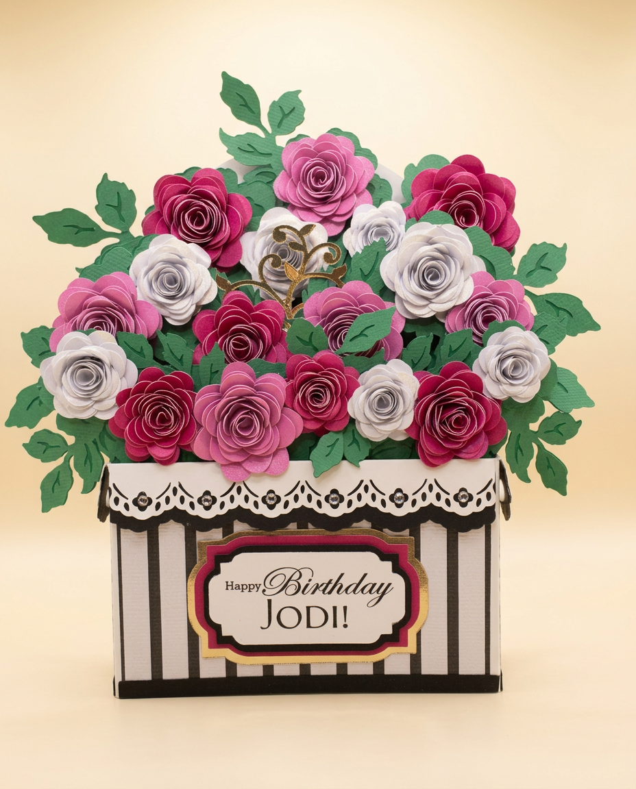 Black and white striped keepsake overflowing with magenta, orchid and pearl-white paper roses and a 'Happy Birthday Jodi!' plaque